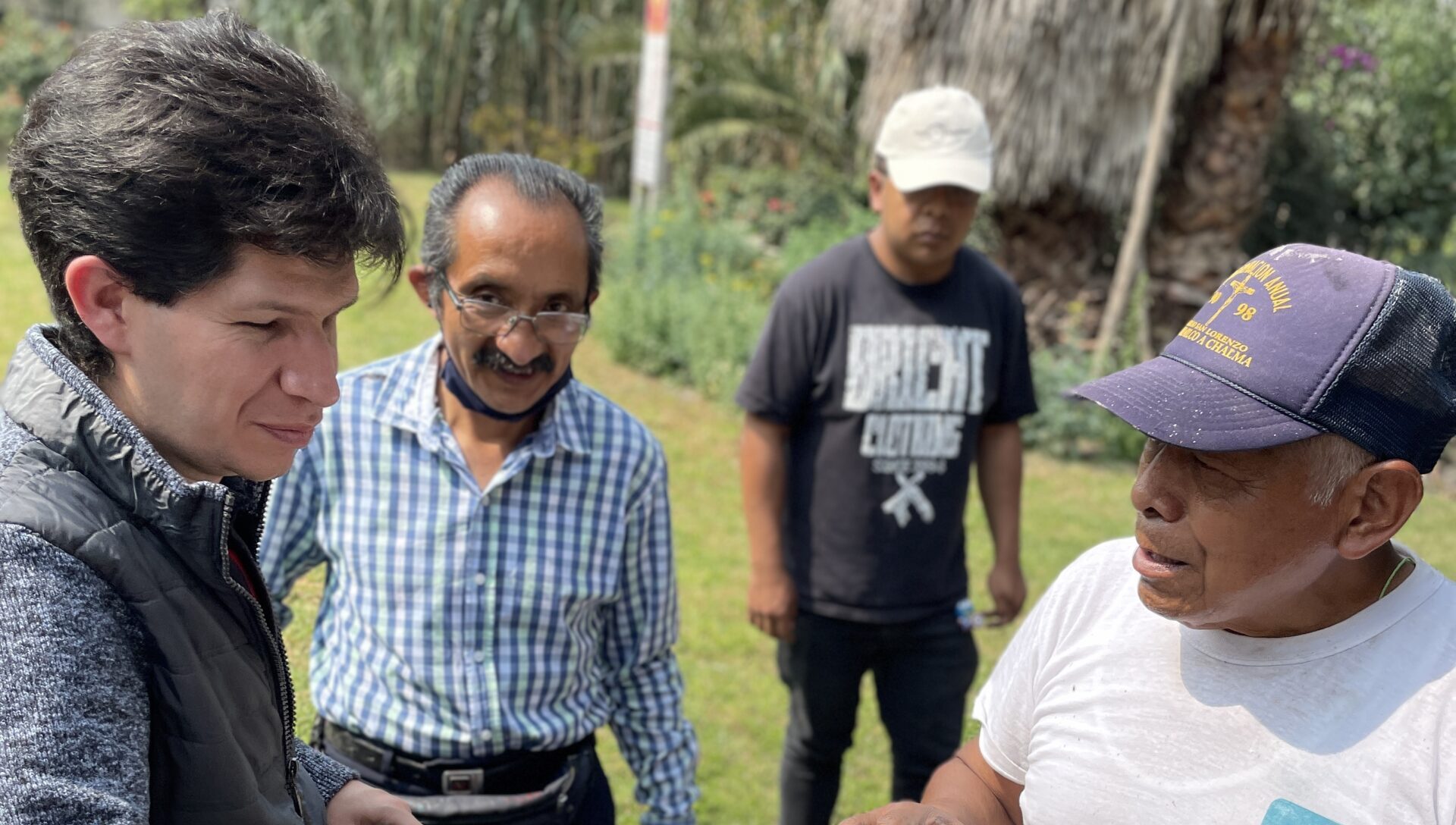 Fotografía horizontal donde aparecen cuatro individuos: una persona con discapacidad visual, dos guías de turistas y un habitante de Xochimilco, quienes se están capacitando para recibir a turistas con discapacidad en su chinampa.