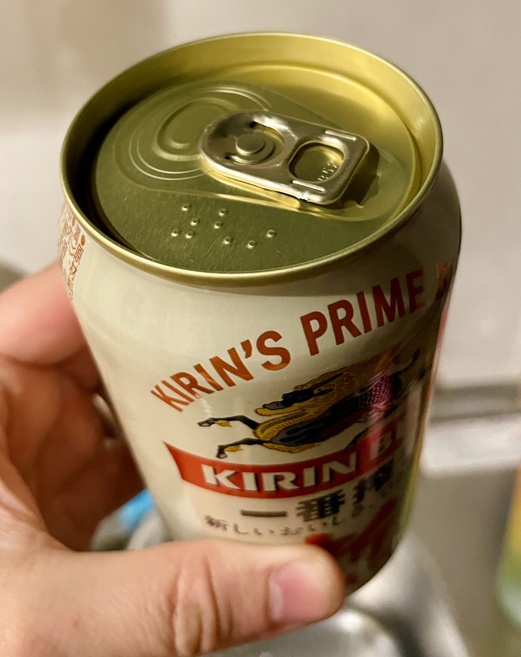 Fotografía de una lata de cerveza marca Kirin sostenida por una mano. En la parte superior, junto a la anilla hay marcas en braille, indicando que es una bebida alcohólica.