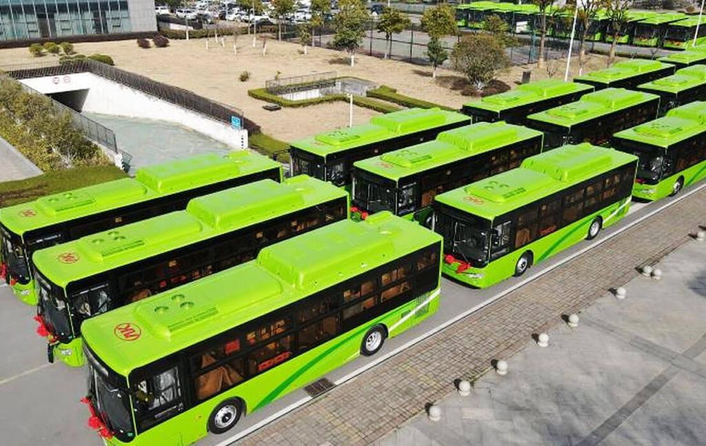 Fotografía de los nuevos autobuses de Nuevo León vistos lateralmente desde arriba, estacionados en una explanada. Son tres filas de autobuses, que van formados de izquierda a derecha. Todos los autobuses son color verde claro, con una franja verde más oscura en su lateral y ventanas oscuras.