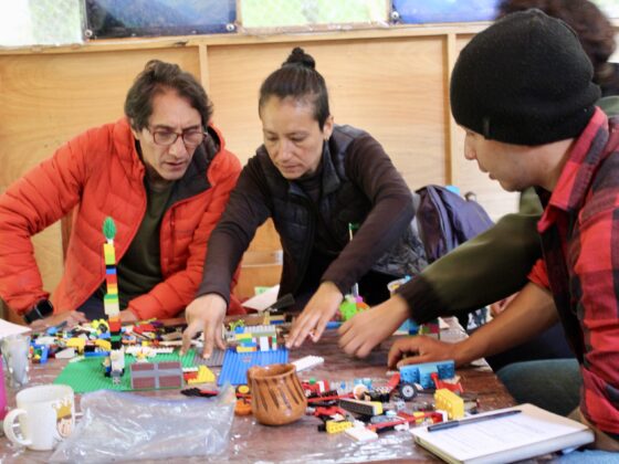 Fotografía de cuatro guías turísticos construyendo con legos sobre una mesa, durante un curso del IMETAC.