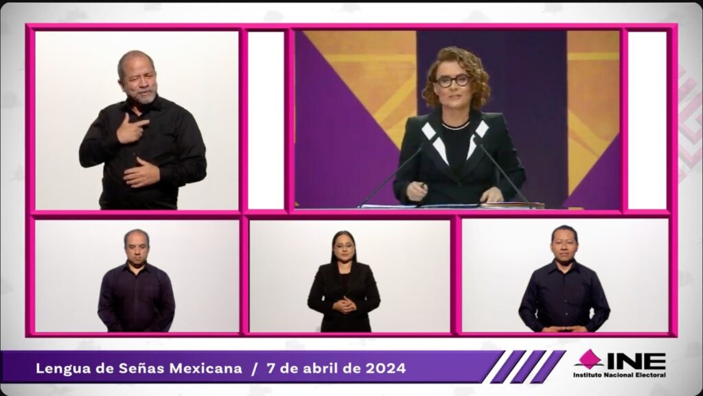 Captura de pantalla del primer debate presidencial, en abril 2024. La pantalla está dividida en 5, cuatro espacios muestran a los intérpretes de lengua de señas mexicana, correspondientes a cada candidato y a los moderadores. En el quinto espacio aparece la moderadora, Denise Maerker.