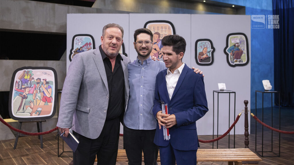 Foto de Cristóbal y Alfonso, fundadores del IMETAC, junto con Marcus Dantus, uno de los tiburones de Shark Tank México. Detrás de ellos se ve un museo accesible, conformado por ilustraciones impresas como cuadros de gran tamaño en la pared y sus respectivas réplicas táctiles hechas con impresión 3D, colocadas en estantes de diferentes alturas.