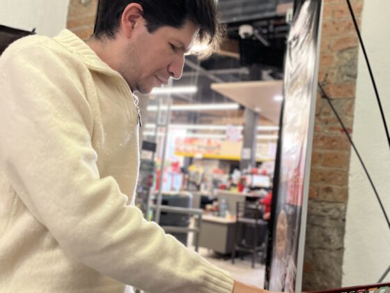 Foto de un hombre con discapacidad visual tocando un mapa háptico en la entrada del Oxxo accesible de Paseo Molinos.