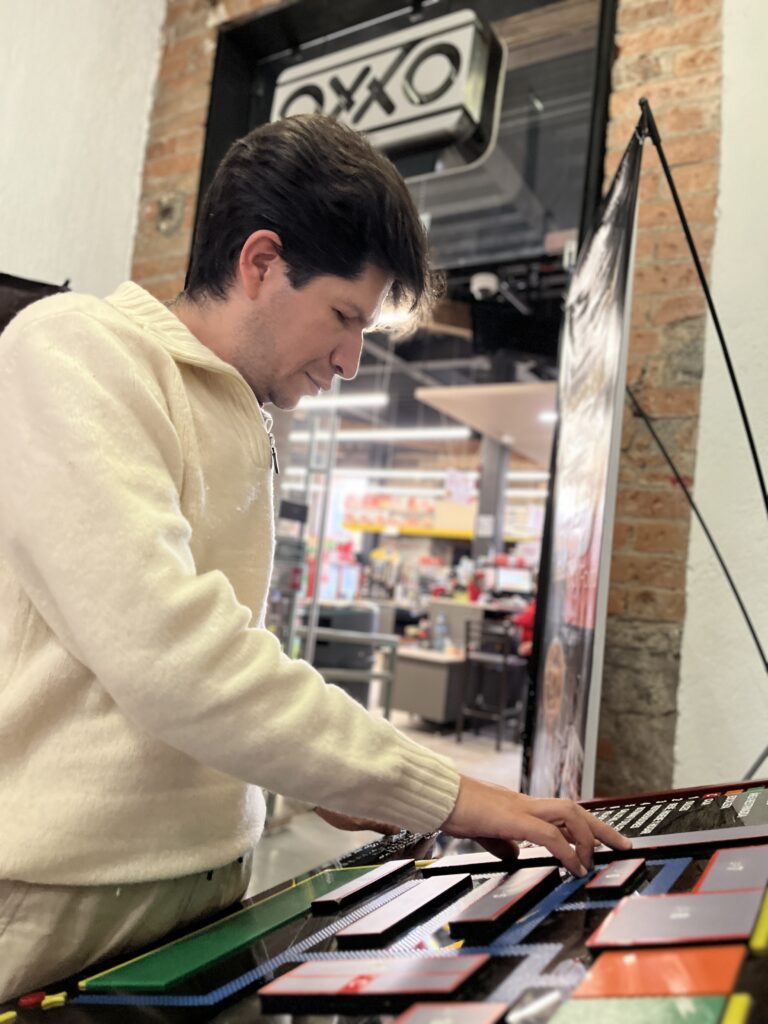 Foto de un hombre con discapacidad visual tocando un mapa háptico en la entrada del Oxxo accesible de Paseo Molinos.