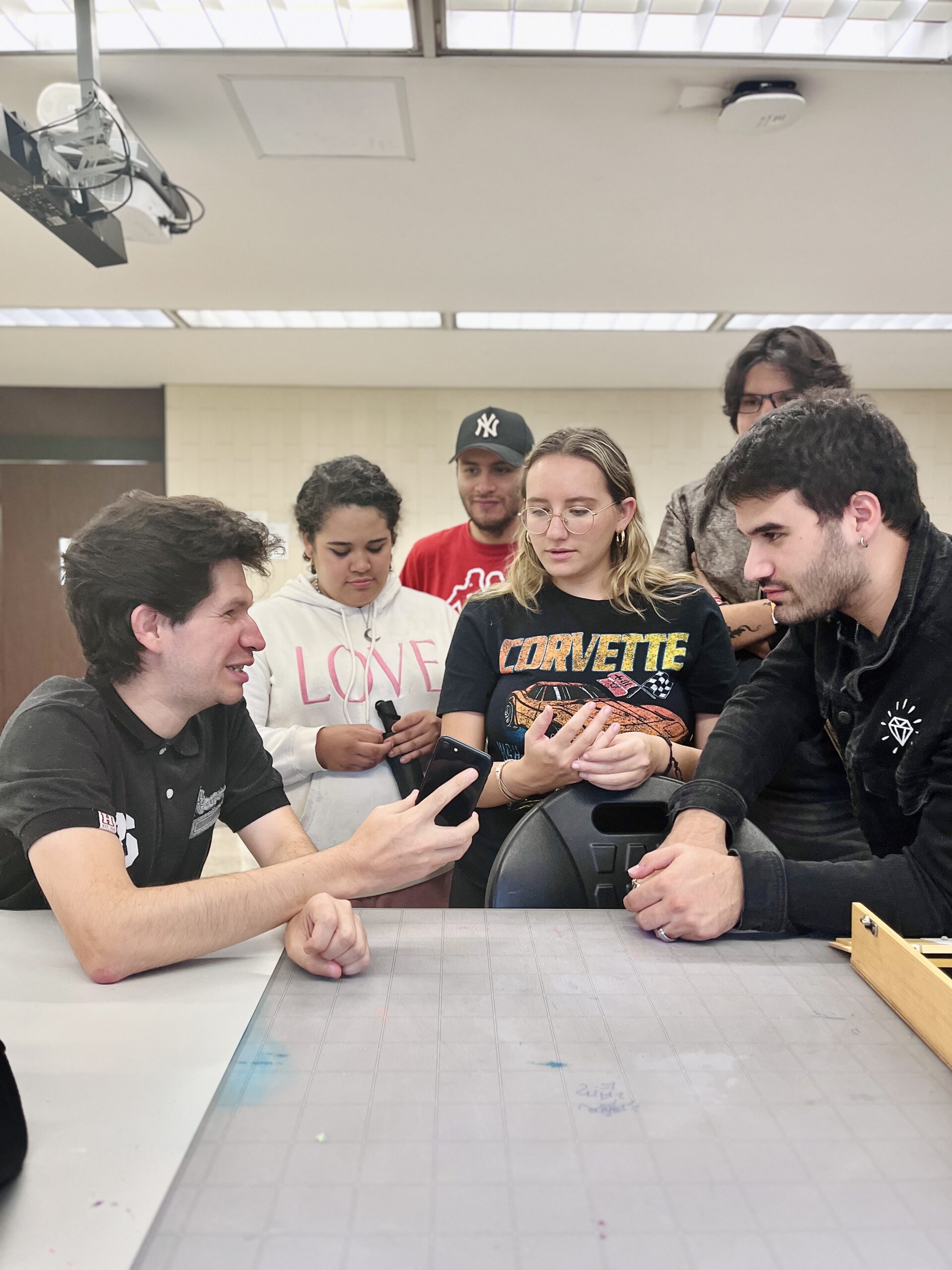 Foto de un hombre con discapacidad visual mostrando cómo utiliza su celular a un grupo de alumnos en una universidad.