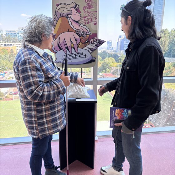 Foto de una mujer con discapacidad visual tocando una réplica impresa en 3D de una obra en un museo. Junto a ella, un guía le explica de qué trata la pieza.