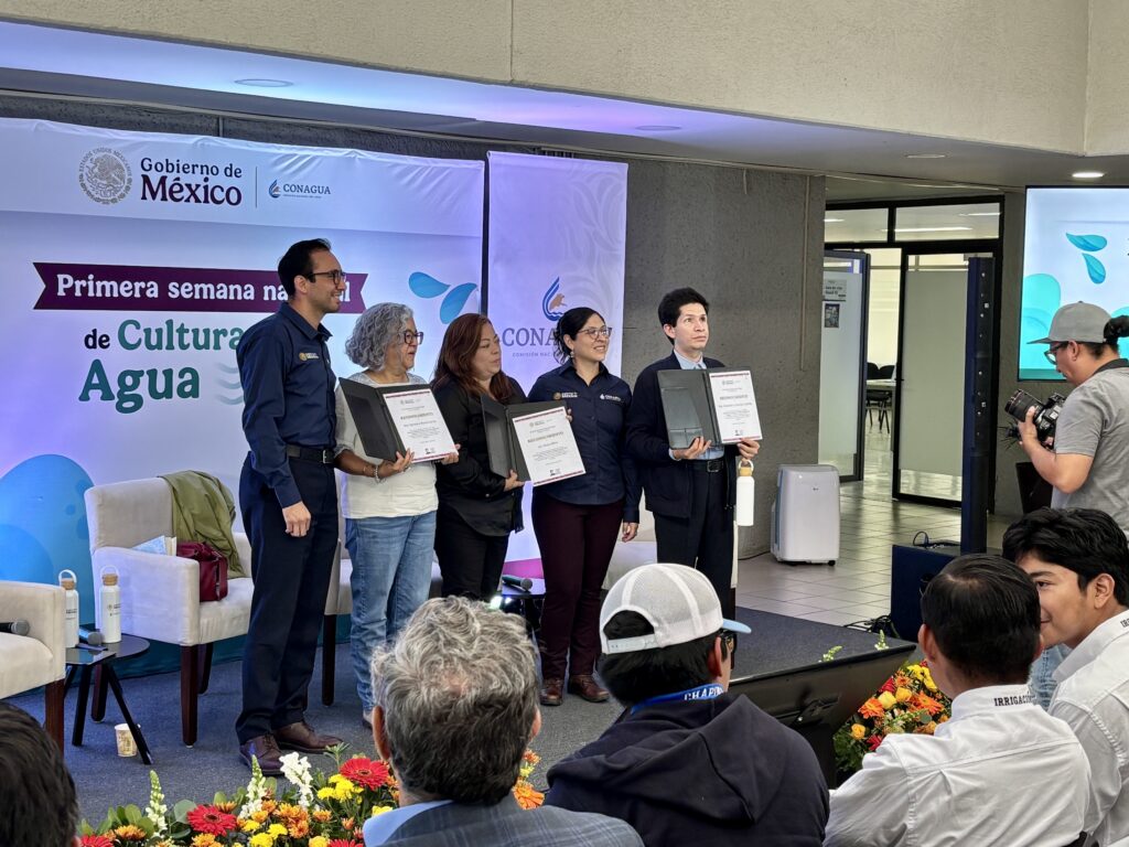 Foto del escenario de la semana nacional de la cultura del agua, donde posan 5 personas, entre ellas el director del IMETAC Cristóbal Sánchez, sosteniendo reconocimientos por haber participado en la ponencia “cultura de agua inclusiva”.