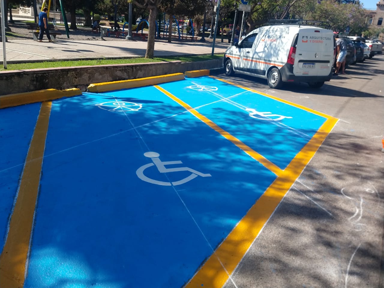 Foto horizontal donde se aprecia un lugar de estacionamiento al aire libre con un símbolo antiguo de accesibilidad dibujado en el piso para comunicar que ese espacio esta reservado.